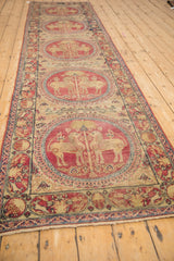 Angled perspective of an antique Kerman runner's column of cochineal red pictorial medallions.