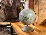 Angled view of vintage Replogle Moon globe, showing cratered surface and piggy bank slot.