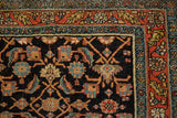Corner detail of a fine antique Serapi rug showing the navy Herati field and intricate terracotta border.