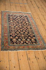 Perspective view of a fine antique Serapi rug with its navy Herati field and terracotta border.