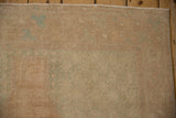 Distressed Oushak runner's soft texture and faded plant motifs in pale sand and ocean green.
