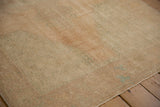 Textured pile of a distressed Oushak runner with even wear, pale sand tones.