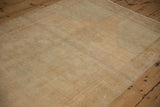 Distressed vintage Oushak rug showing low pile texture in pale sand and muted green.