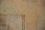 Vintage distressed Oushak runner's textured pile and hand-knotted foundation in pale sand and green.