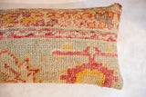Textured hand-knotted vintage Turkish rug fragment in faded red, yellow, and pale blue.