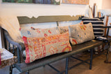 Vintage Turkish rug fragment pillow, side view of its textured red, orange, and beige design.