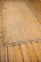 Long perspective view of a distressed Oushak runner in a pale gold and faded pink palette.