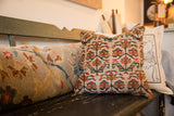 Vintage Kurdish rug fragment pillow showing textured red, blue, and yellow florals.