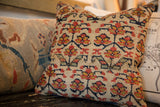 Vintage Kurdish rug fragment pillow with worn red, gold, and navy floral motifs.