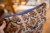 Textured vintage Kurdish rug fragment pillow, abstract floral motifs, deep blue edge.