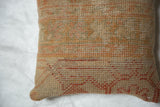 Woven texture detail of a vintage Turkish rug fragment pillow in muted orange and beige.