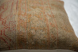 Vintage Turkish rug fragment pillow's woven texture in muted beige and rust hues.