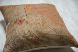 Textured weave of a vintage Turkish rug fragment pillow in muted orange and beige.
