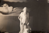 Vintage photograph featuring a blurred figure with surreal draping and abstract background.