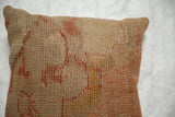 Distressed surface of a vintage Turkish rug pillow in muted orange and beige.