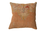 Distressed vintage Turkish rug fragment throw pillow with muted orange, beige, and gold geometric pattern, 18x18 inches.