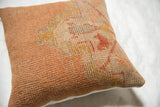 Close-up of vintage Turkish rug fragment pillow, showing distressed peach and gold geometric patterns.