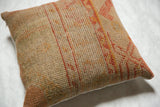 Vintage rug fragment pillow's textured weave with linear orange and beige designs.
