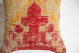 Richly textured weave featuring bold red and gold geometric motifs on the rug fragment pillow.