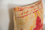 Corner of antique rug fragment pillow with handwoven beige, red, and orange accents.
