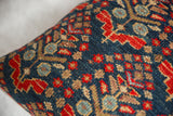 Textured vintage rug fragment pillow in deep blue, red, and tan geometric patterns.