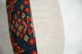 Side view of vintage rug fragment pillow, showing patterned wool and neutral remnant fabric.