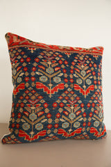 Vintage hand-knotted rug fragment pillow featuring deep blue and ruby red motifs.