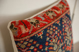 Vintage Rug Fragment Throw Pillow, textured hand-knotted pile, deep red border, indigo blue motifs.