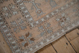 Angled view of a vintage Oushak rug corner showing the geometric border and distressed, low-pile texture.
