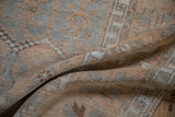 The soft, distressed pile and hand-knotted texture of a folded vintage Turkish Oushak rug.