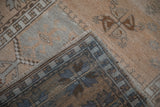 Folded corner of a vintage Oushak rug displaying its hand-knotted reverse and low-pile texture.