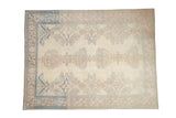 A distressed vintage Oushak rug with oversized palmettes in pale dusty rose and blue on an ivory field.