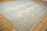 A distressed vintage Oushak carpet's soft floral pattern in pale rose and sky blue hues.
