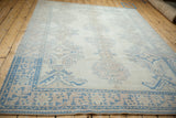 A low perspective across a vintage Oushak rug, detailing the even wear on its geometric patterns.