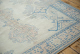 Even, low pile wear on a distressed Oushak corner with blue and dusty rose motifs.