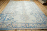Angled perspective of the distressed Oushak rug, showing its overall muted pastel design.