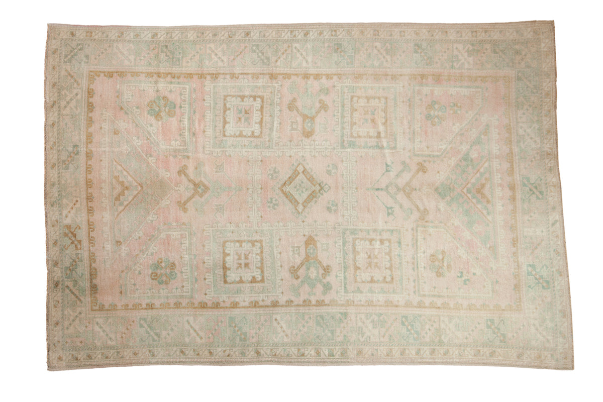 Vintage distressed Oushak carpet with a geometric grid design in soft pink, baby teal-blue, and dusty gold.