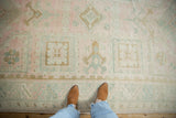 Overhead view of the faded geometric details in soft pink and teal on a vintage distressed Oushak rug.
