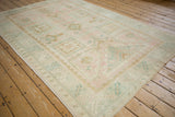 Soft pink and ivory patterns on the evenly worn pile of a vintage Oushak carpet.