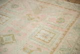 Subtle grid-like geometric design in gold and teal on a distressed pink vintage Oushak carpet.