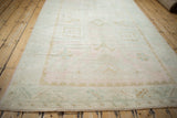 A long, angled view of the distressed Oushak rug's soft, geometric grid design.