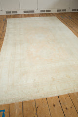 Angled view of a vintage Oushak carpet highlighting its soft, distressed texture and muted sandalwood color.