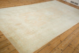 Angled view of a distressed Oushak carpet showing its soft, time-softened pale tangerine palette.