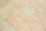 Close-up of a vintage rug's soft, low pile with a distressed wash of pale tangerine color.