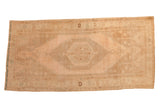 Vintage distressed Oushak runner with a stepped medallion in a soft palette of apricot, sand, and ivory.