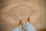 A vintage distressed Oushak runner's even wear and soft, abrashed texture in sand and pale apricot hues.