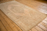 Angled shot of a distressed Oushak runner showing the faded medallion and even, low-pile wear.