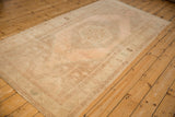 Angled view of a vintage Oushak runner showing its abrashed, low pile and faded blush tones.