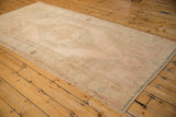 A vintage Oushak runner viewed at an angle, emphasizing its length and softly worn, sandy tones.