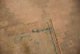 A folded corner reveals the hand-knotted construction on the back of a distressed Oushak rug.